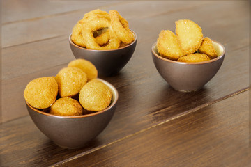 Fast food products: olive all'ascolana, onion rings and chicken nuggets on wooden table