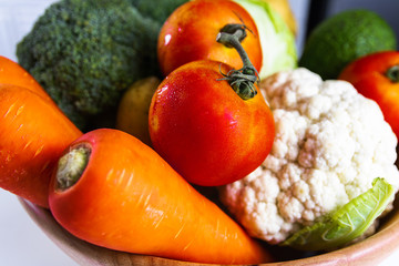 Tomatoes, carrots, cauliflower, avocado in a wooden tray