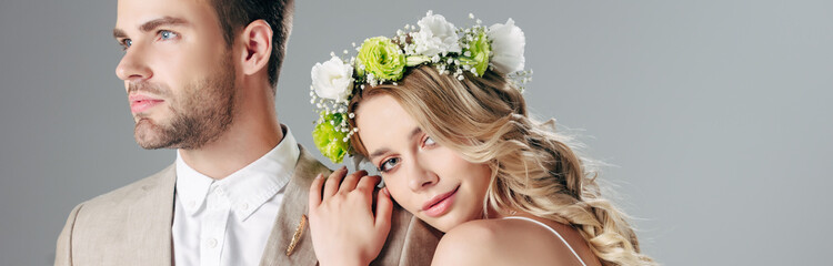 Naklejka premium panoramic shot of attractive bride and handsome bridegroom hugging and looking at camera