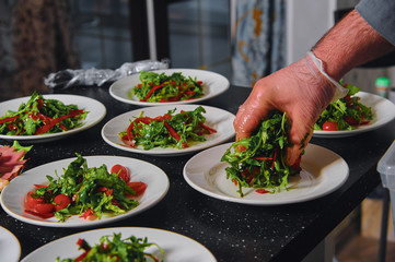 Serving catering salad with vegetables with meat and arugula.