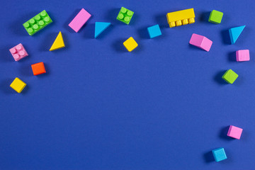 Baby kid toys background. Top view to colorful wooden cubes and plastic construction blocks on blue background
