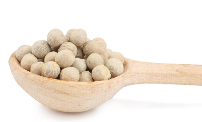 White pepper peas in the wooden spoon isolated on white