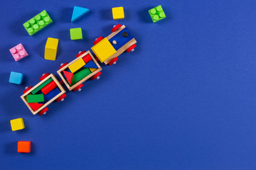 Obraz premium Drewniany pociąg zabawka dla dzieci z kolorowymi kostkami na niebieskim tle