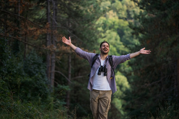 Happy adult man is hiking in forest.