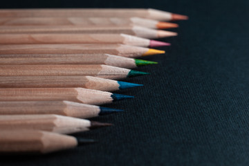 Sharpened pencils of different colors made of light wood isolated on black background.