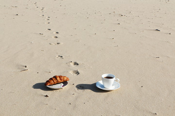 Fototapeta na wymiar A cup of coffee stands on the sandy seashore