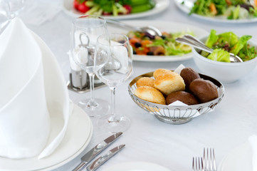 buns of white and black bread on a served table on a background of salads