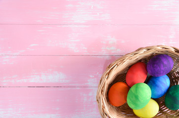 Colorful handmade easter eggs in a basket wiith pastel pink wooden background. Happy Easter Day, Easter eggs concept.