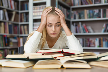 Fatigued girl holding her head and reading book