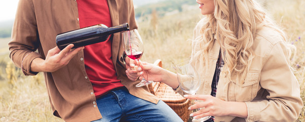 panoramic shot of man pouring wine to glass outside