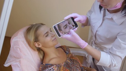 Female beautician makes a photo on the phone while working as a beautician for advertising in social networks. tracking the result before and after. 4k