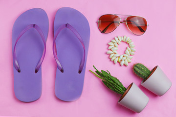 Beach purple flip flops, aviator sunglasses, seashell bracelet and succulent cacti cactus on a pink background flat lay. Summer vacation colorful travel beach flat lay with free copy space for text