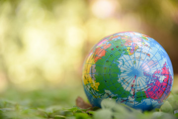 Globe ball on the natural green leaves ground and green bokeh background. World environment day concept, Safe world concept, World Earth Day.