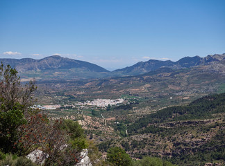 Fototapeta na wymiar El Burgo Town, seen from a Viewpoint high up in the Sierra de las Nieves National Park, set amongst the Olive Groves in the Valley Floor. Spain