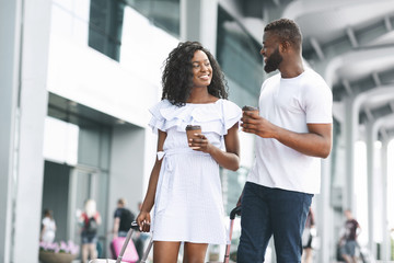 Young african american man and woman flirting with coffee at airport
