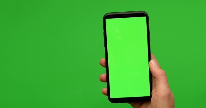 Woman hand holds a smartphone with greeen screen over a green background. Close up footage of hand only
