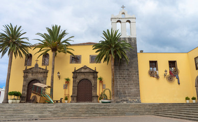 Fototapeta na wymiar Main Square In Garachico With Monastery Of San Francisco, Tenerife, Spain and folk decoration. Palms in a facade from a historic building