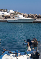 Greece, Sikinos island.  The harbor. In the foreground,  the working machinery of a traditional fishing boat, contrasts with sleek lines of a pleasure boat.
