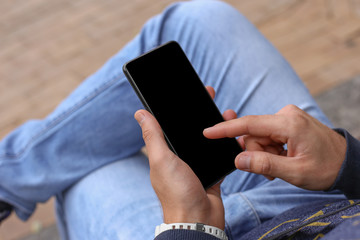 A man on a bench holds a smartphone. Mockup