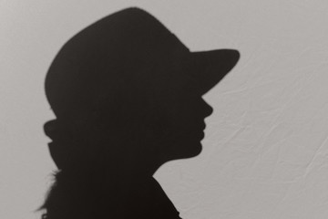 Silhouette of woman wearing a hat, close up. Abstract people concept. Shadow of female face.