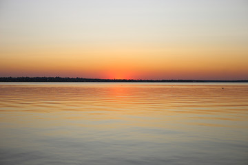 Obraz premium Beautiful red sunset near the river in summer. Sunset at the river near bridge.
