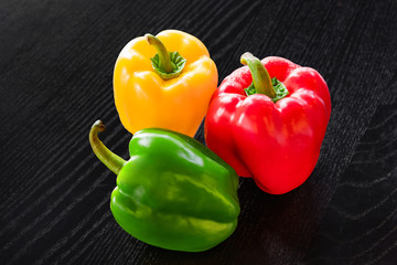 Freshly colored bell pepper in many colors Assemble the green, yellow, and red in a beautiful, bright, photographed position on a black wooden floor