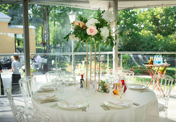 Beautiful composition with flowers on the tables and candles for guests at a wedding or a birthday party