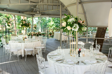 Beautiful composition with flowers on the tables and candles for guests at a wedding or a birthday party