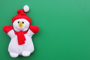 Toy smiling snowman on a green background.