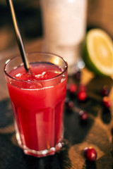 fresh red dink with staw, pomegranade seeds, limone on wooden table