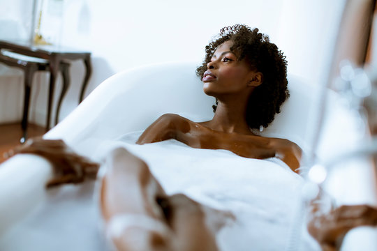 Beautiful african american woman bathing in a tub full of foam