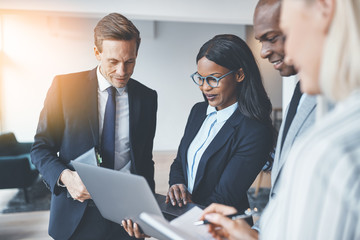 Businesspeople working on a laptop while standing in an office