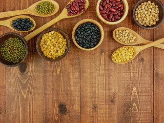 Flat lay,top view assorted beans including red bean,soybeans,black beans,mung beans on brown,beige wooden background with copy space