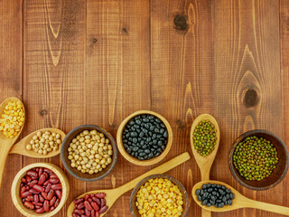 Flat lay,top view assorted beans including red bean,soybeans,black beans,mung beans on brown,beige wooden background with copy space
