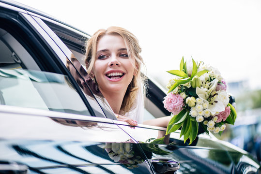 Attractive And Blonde Bride Holding Bouquet And Looking Away