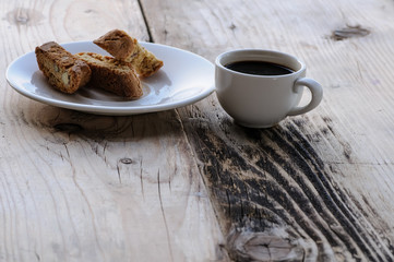 White coffee cup on vintage wooden table with almond cookies