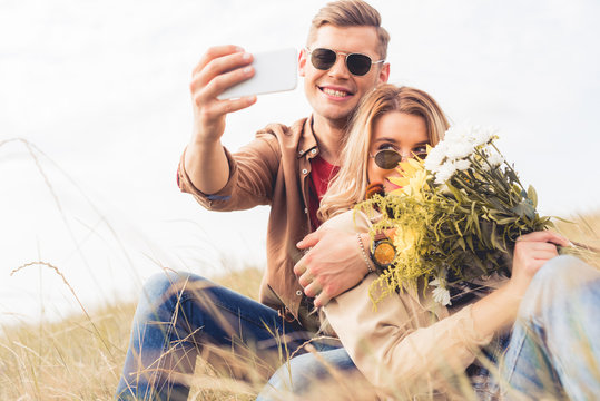 attractive woman with bouquet and handsome man taking selfie