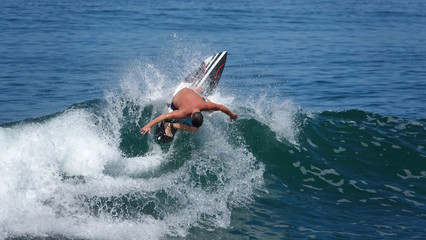 Unrecognizable male surfer on top of wave