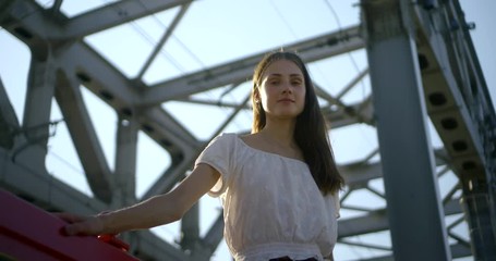 girl with long loose hair dances on bridge at red handrails