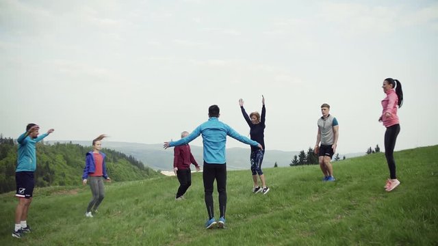 Large group of fit and active people doing exercise in nature.