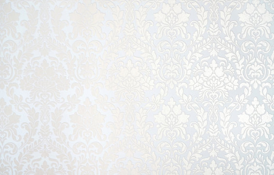 Beautiful texture of paper Wallpaper embossed in form of a classic floral ornament in light golden beige and white tones.