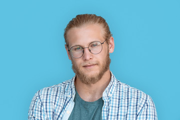Young bearded handsome man blond hair hipster face wearing optical glasses looking at camera,...