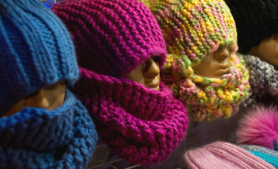 Fototapeta na wymiar Multi-colored knitted hats and scarves on mannequins. Soft and comfortable winter clothes.