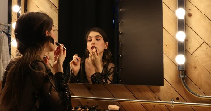 Glamorous female applying lipstick