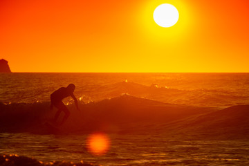 Fototapeta na wymiar man surfing at sunset