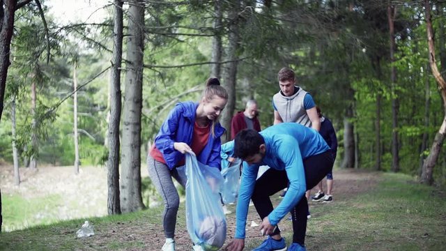 Group of fit people picking up litter in nature, a plogging concept.