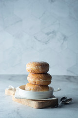 Delicious sugar donuts on a white plate, rustic style.