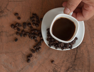 People holding coffee cups and coffee beans on a wooden table