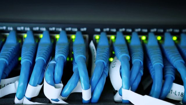 Server rack with blue internet fiber optic cables connected to patch panel in server room. Concept of connecting the signal system Internet.Digital technology.Cyber business.Networking