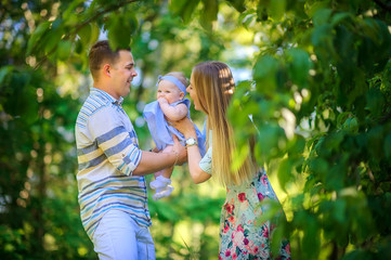 Obraz premium Happy young family is relaxing outdoors. Walk in the park with a child in her arms. having fun